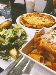 A hearty, Italian spread at Aglio e Olio. Pasta bowl, caesar salad, and pizza.